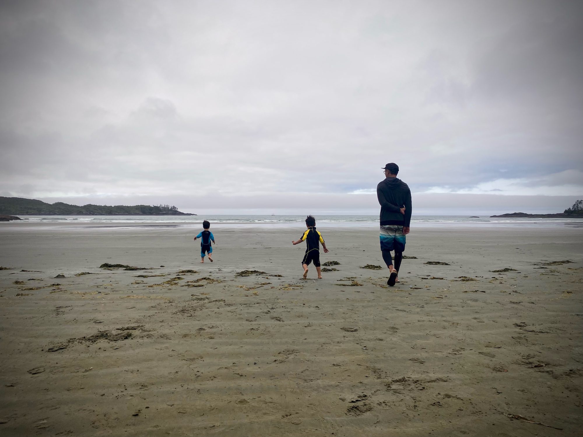 Two boys leading a man (their father) on a beach